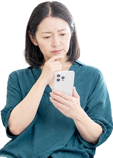 スマートフォンを見て売却について悩む女性